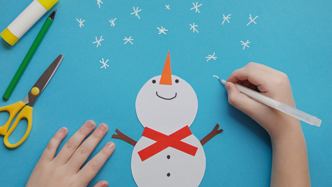 hands doing paper craft. snowman cut out