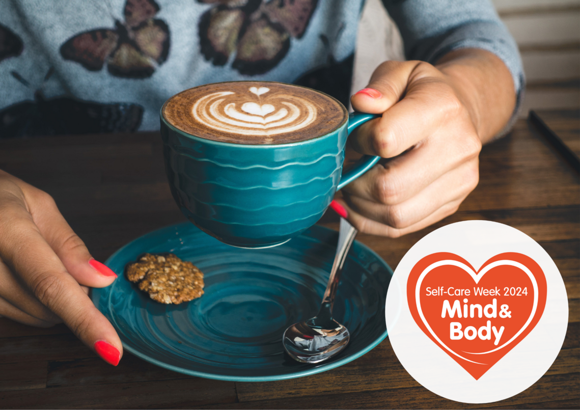 woman sat at a table holding a cup of coffee. 