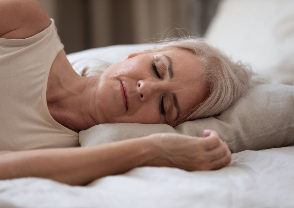 Lady lies on pillow on her side with her eyes closed 