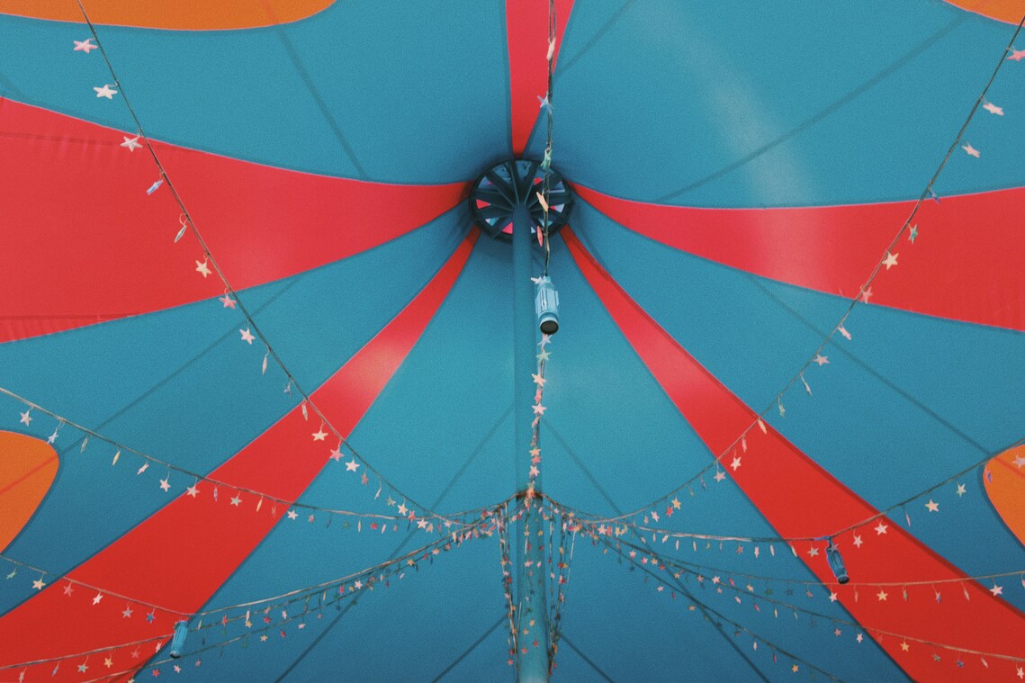 A view from the ground of the inside of a blue and red striped circus tent with strings of stars
